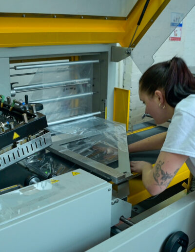 production staff at teesh print ltd working with an automated packing machine