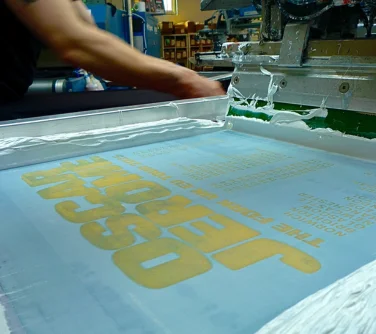 close up of a mesh screen with white ink on a rotary screen printing press.