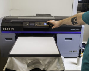 a white t shirt fixed onto a direct to garment machine, ready for t shirt printing