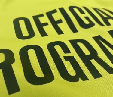 close up of black text professionally heat pressed onto a yellow garment.