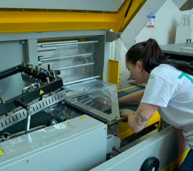 person operating an automated packing machine for folded clothing.