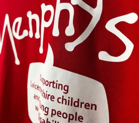 close up of a red activewear t shirt with a white print for 'Menphys' charity with text that reads "supporting Leicestershire children and young people with disabilities"