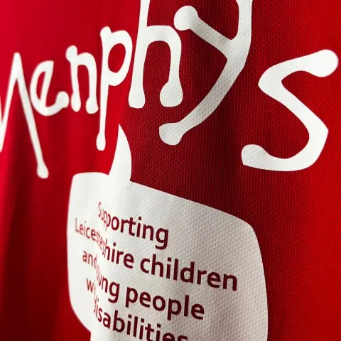 close up of a red activewear t shirt with a white print for 'Menphys' charity with text that reads 