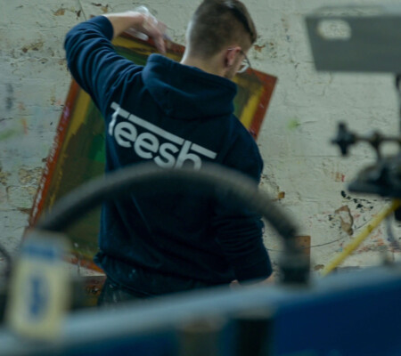 A person holding a screen printing mesh screen in an industrial clothing printing business warehouse.