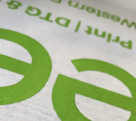 Close up of the Teesh Print Ltd logo screen printed in green onto a white t-shirt, showing the detail of the ink vibrancy.