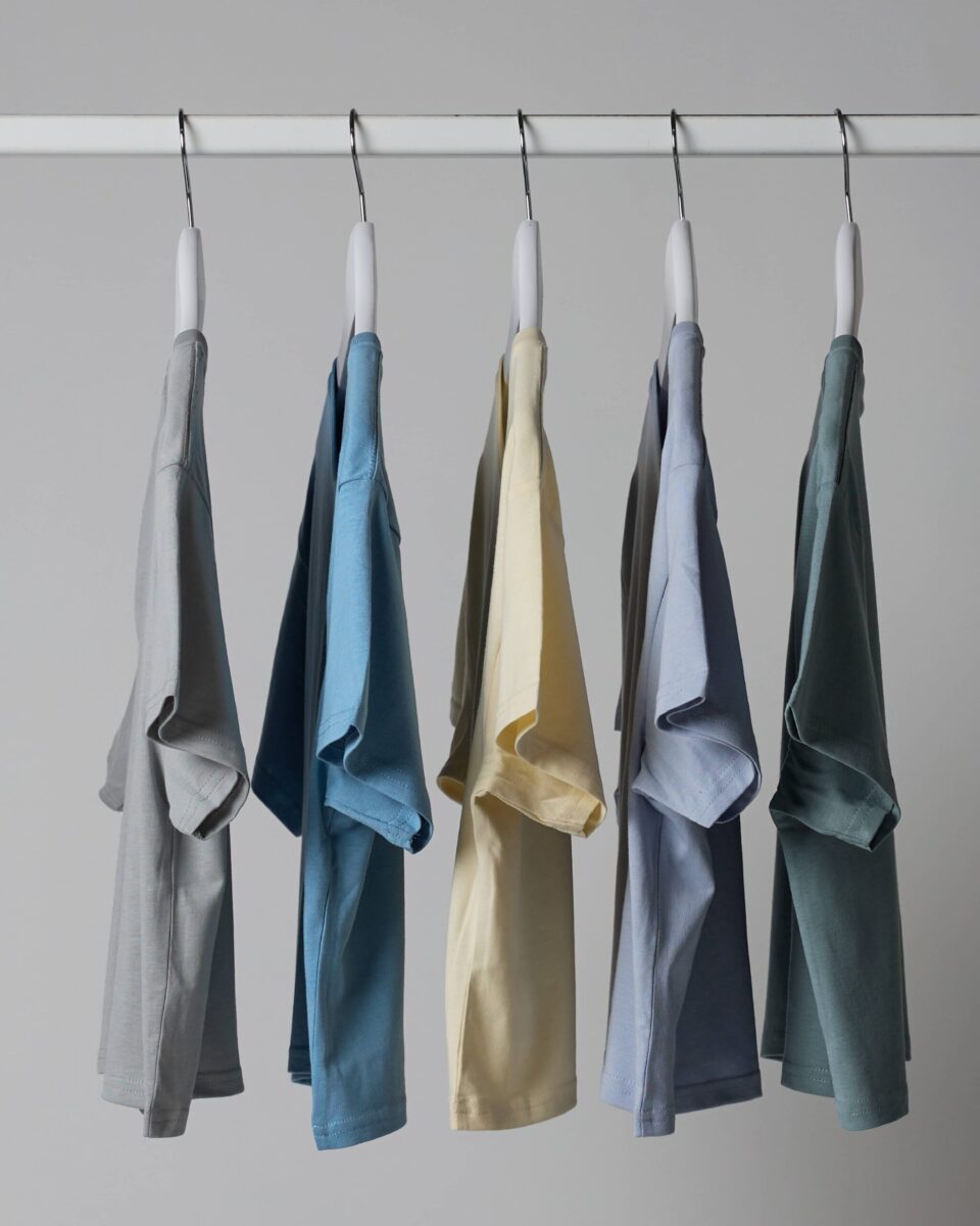 a row of different coloured t shirts hanging on a clothes rail