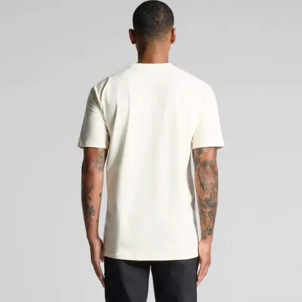 A person wearing the AS Colour 5026 Classic Tee in natural colour, regular fit, standing to showcase the plain back design.