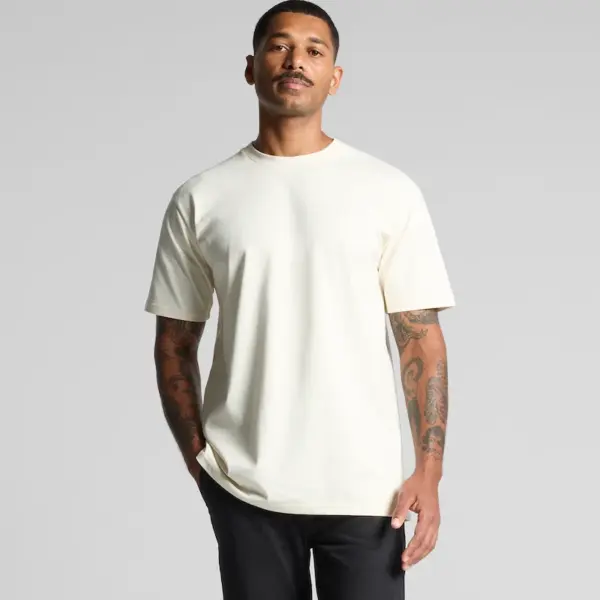 A person wearing the AS Colour 5026 Classic Tee in natural colour, regular fit, standing casually to showcase the plain front design.