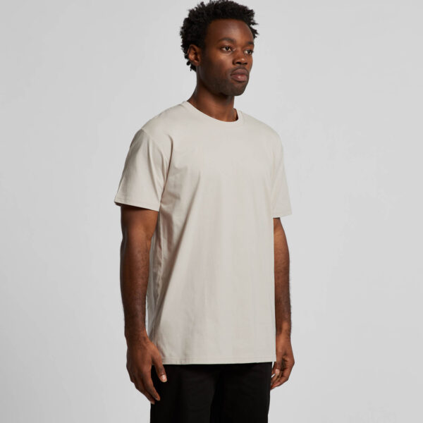 Person wearing a natural T-shirt and black trousers against a plain background.