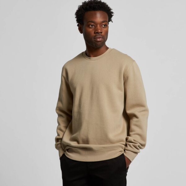 a model wearing a sand coloured sweatshirt facing the camera with their hands in their pockets