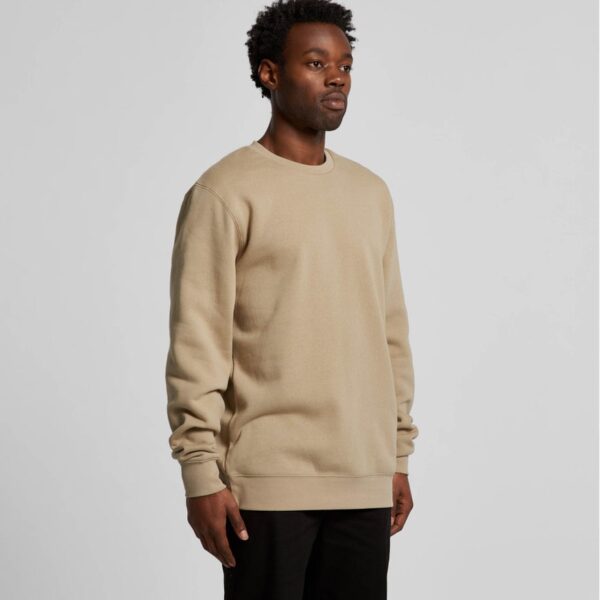 a model wearing a sand coloured sweatshirt stood on an angle to the camera.