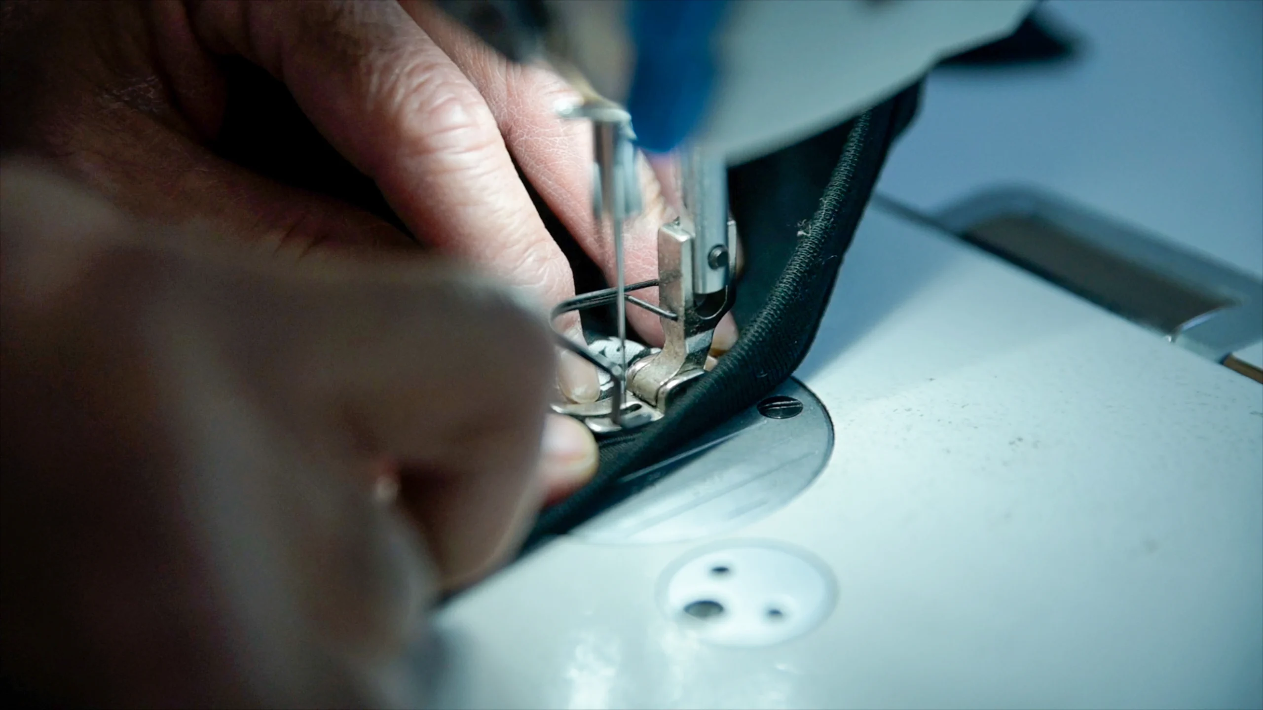 close up of hands sewing a neck label into a t shirt