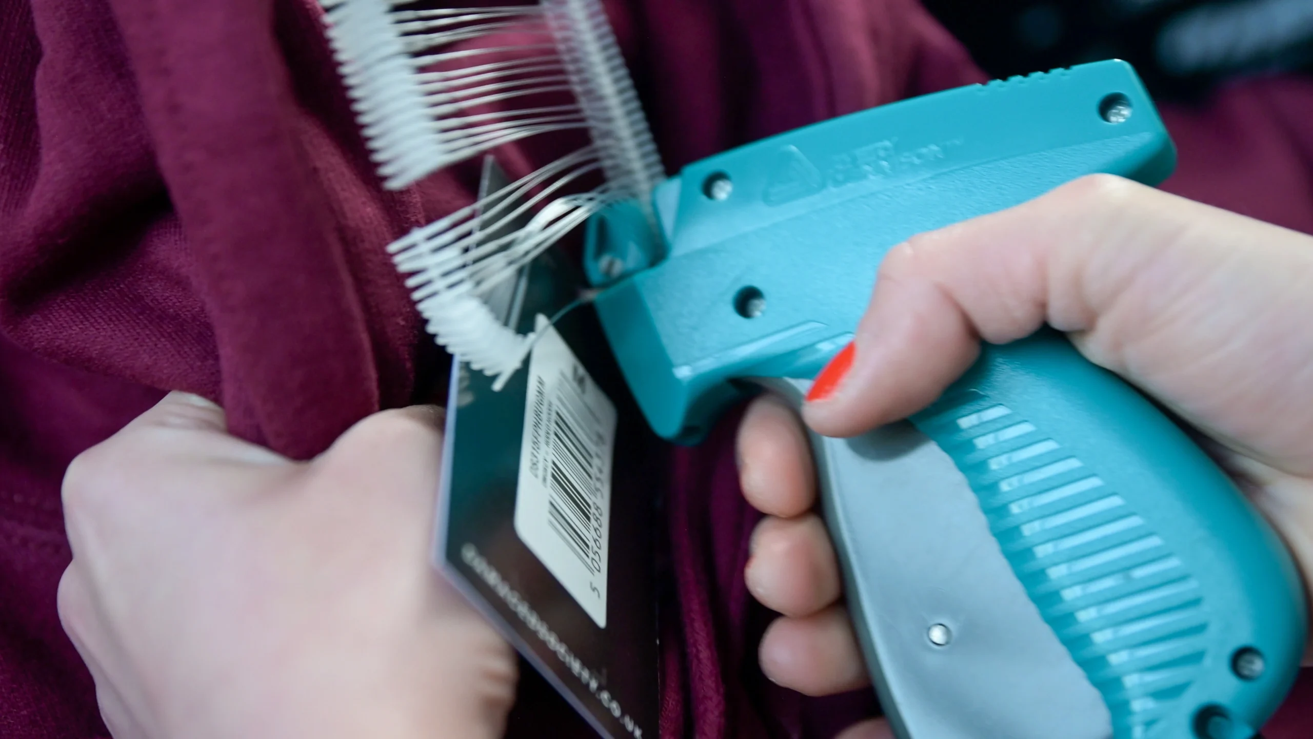 hands using a kimble tagging gun attaching a swing tag to a garment