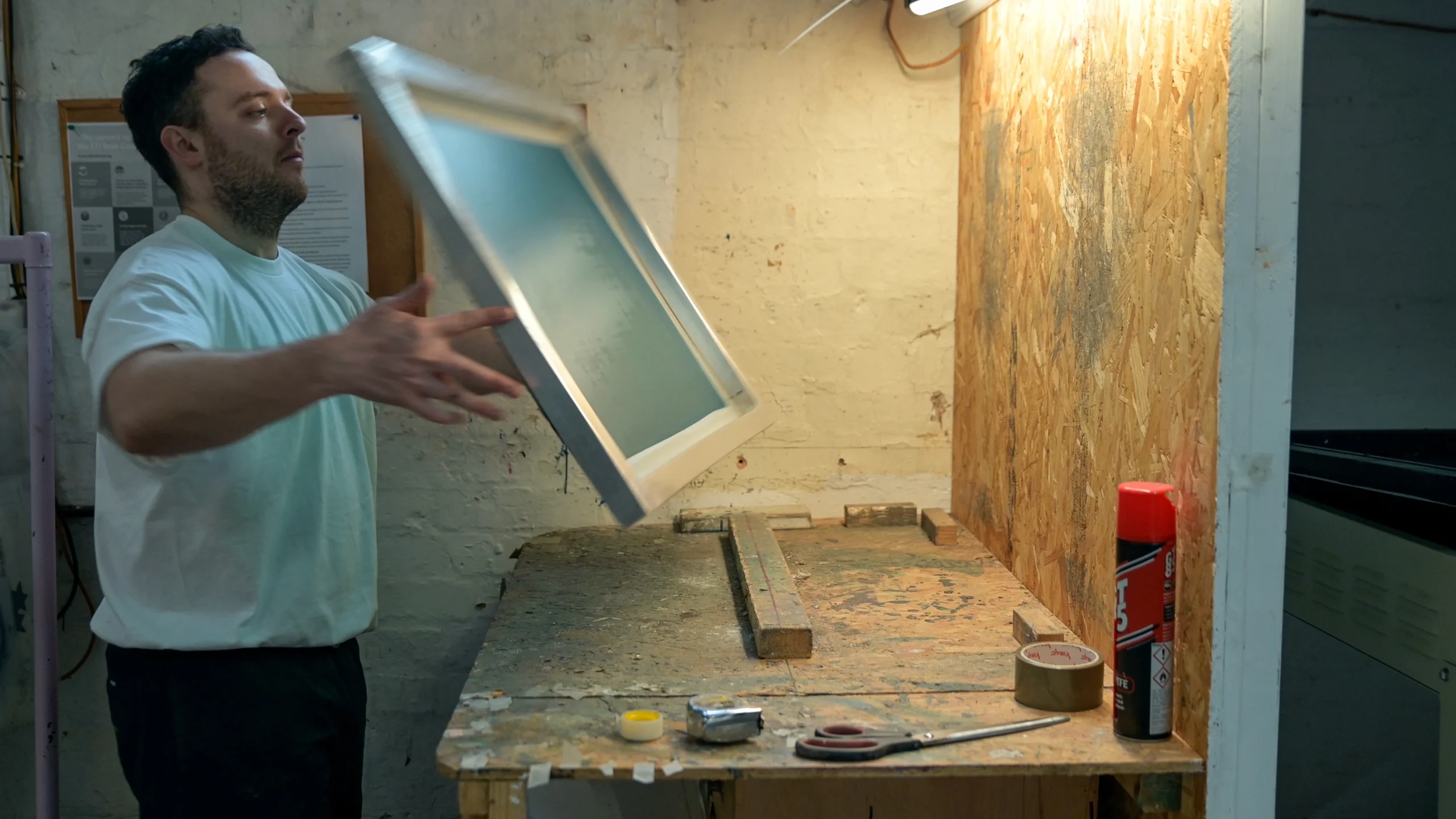 A person with a screen printing frame, flipping it over