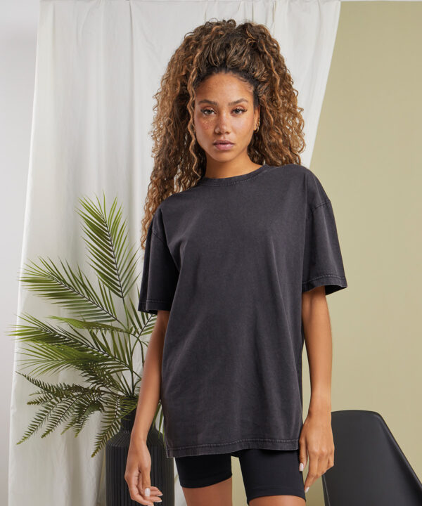 Women's oversized acid wash tee in graphite grey modelled with black cycling shorts in front of a neutral, clean background