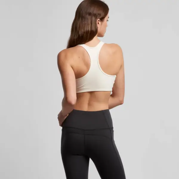 Off-white racerback sports bra with racerback design shown from back view with black leggings.