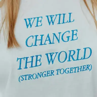 white t shirt with blue embroidered design text that reads "we will change the world (stronger together)".